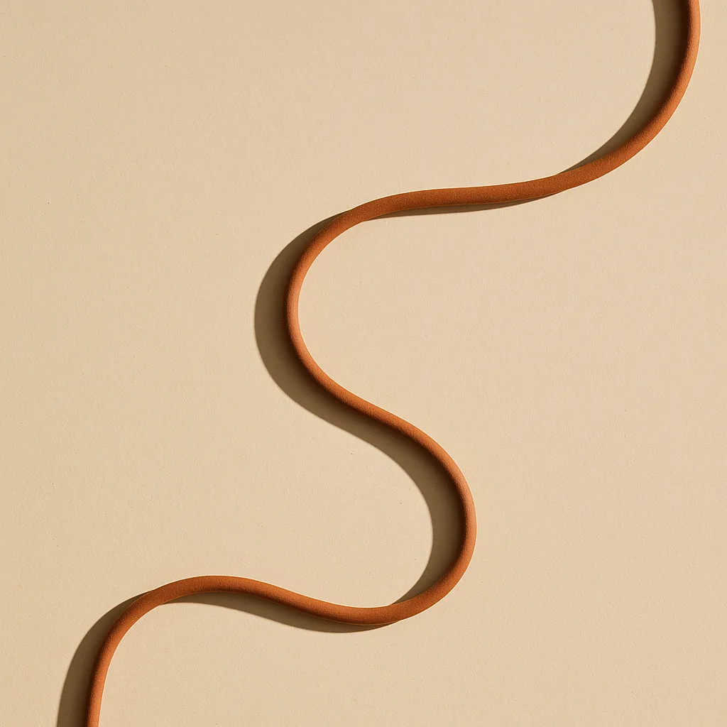 A single terracotta cord laid in one continuous, unbroken path across a cream surface