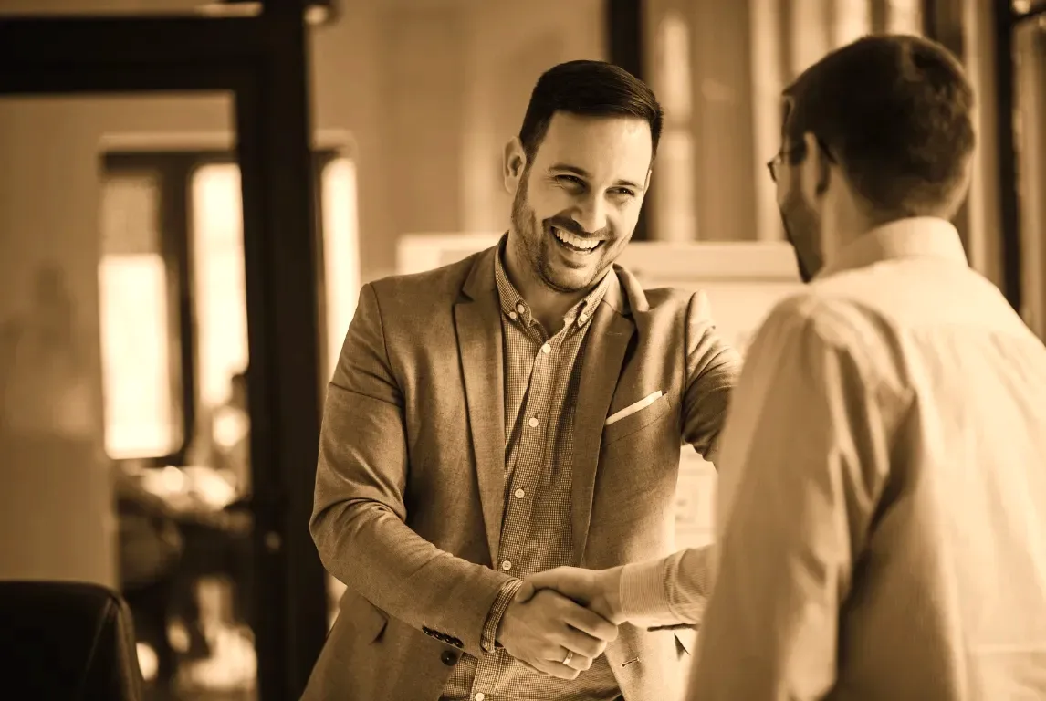 A broker and a business owner shaking hands after settling a consolidation that had been written off as impossible.